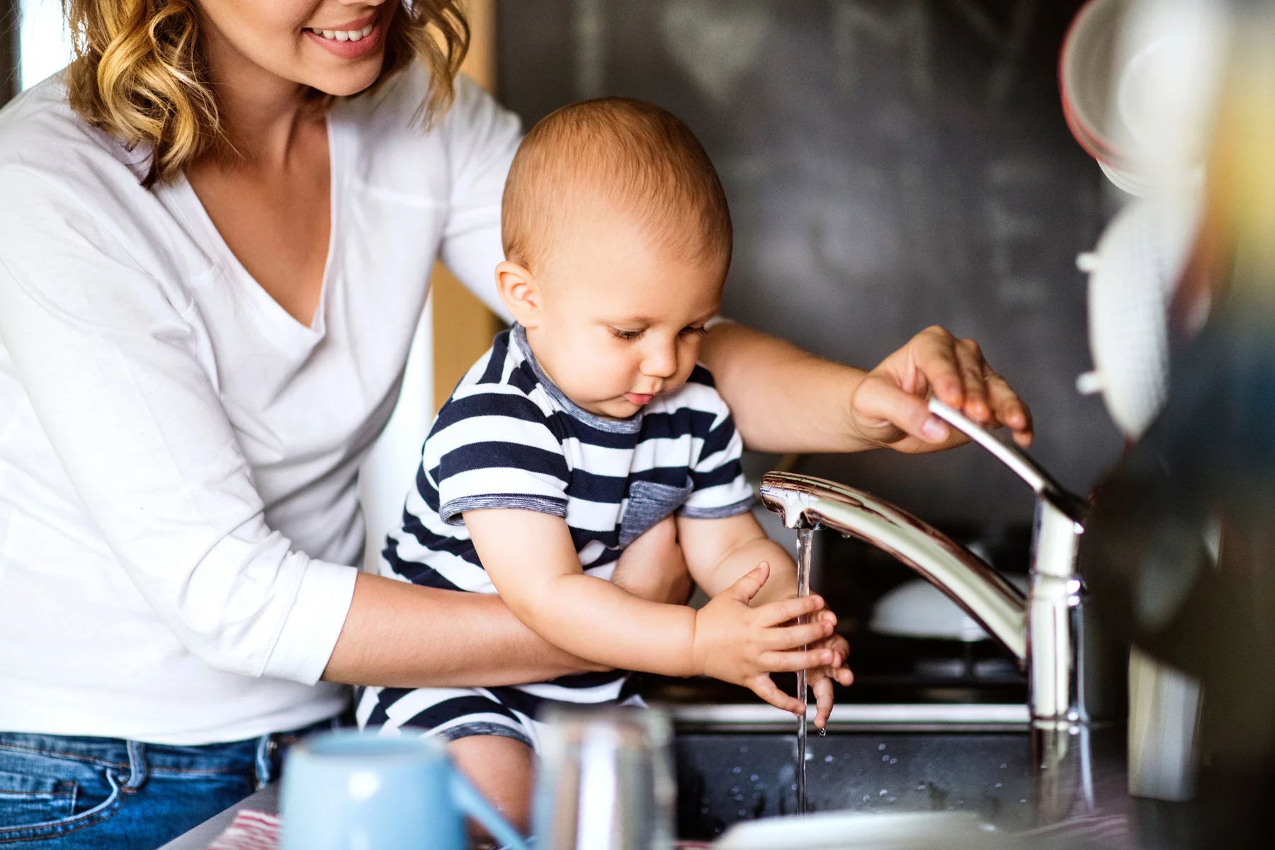Mom with baby pouring tap water