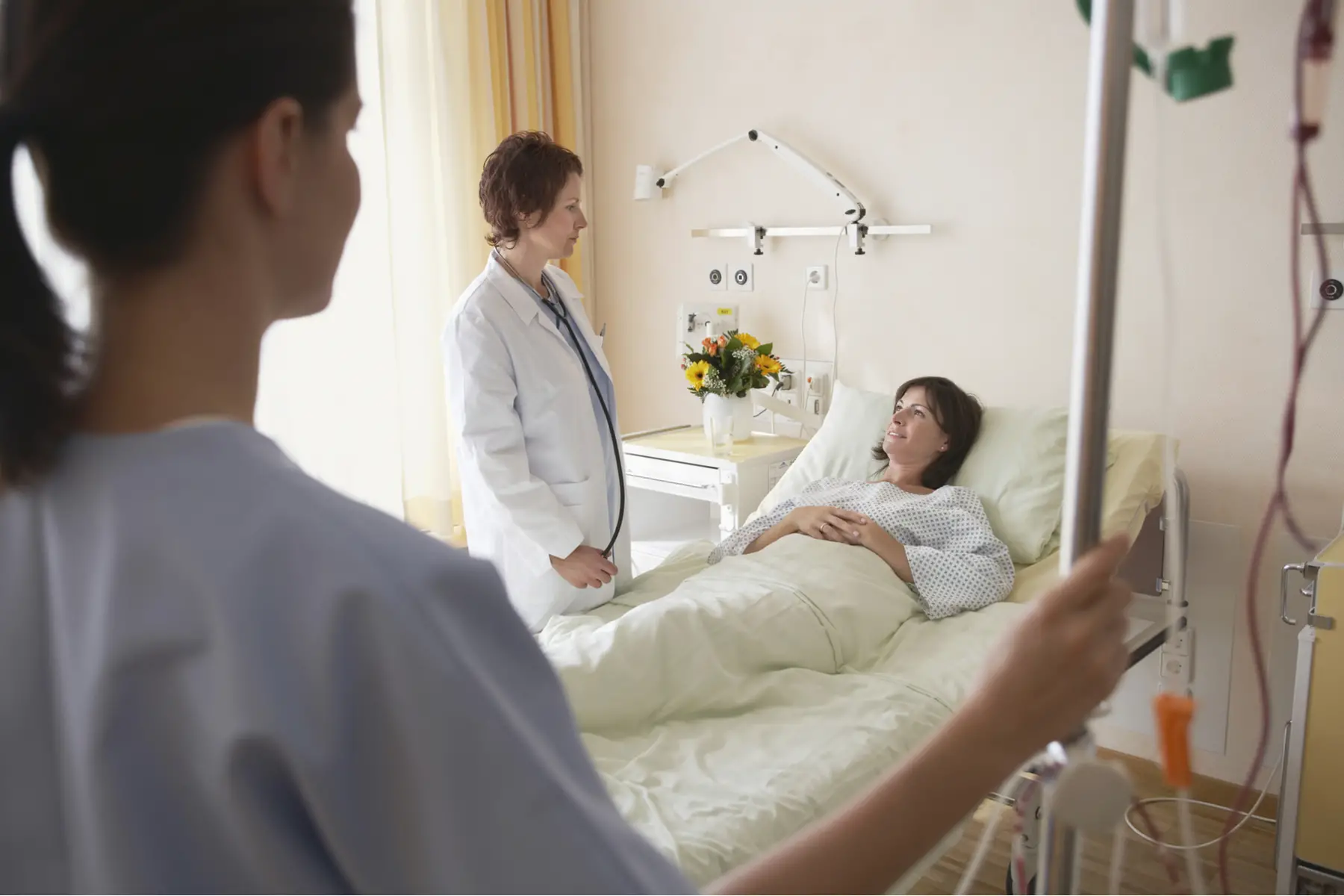 a patient chatting with a doctor and nurse in a private hospital room