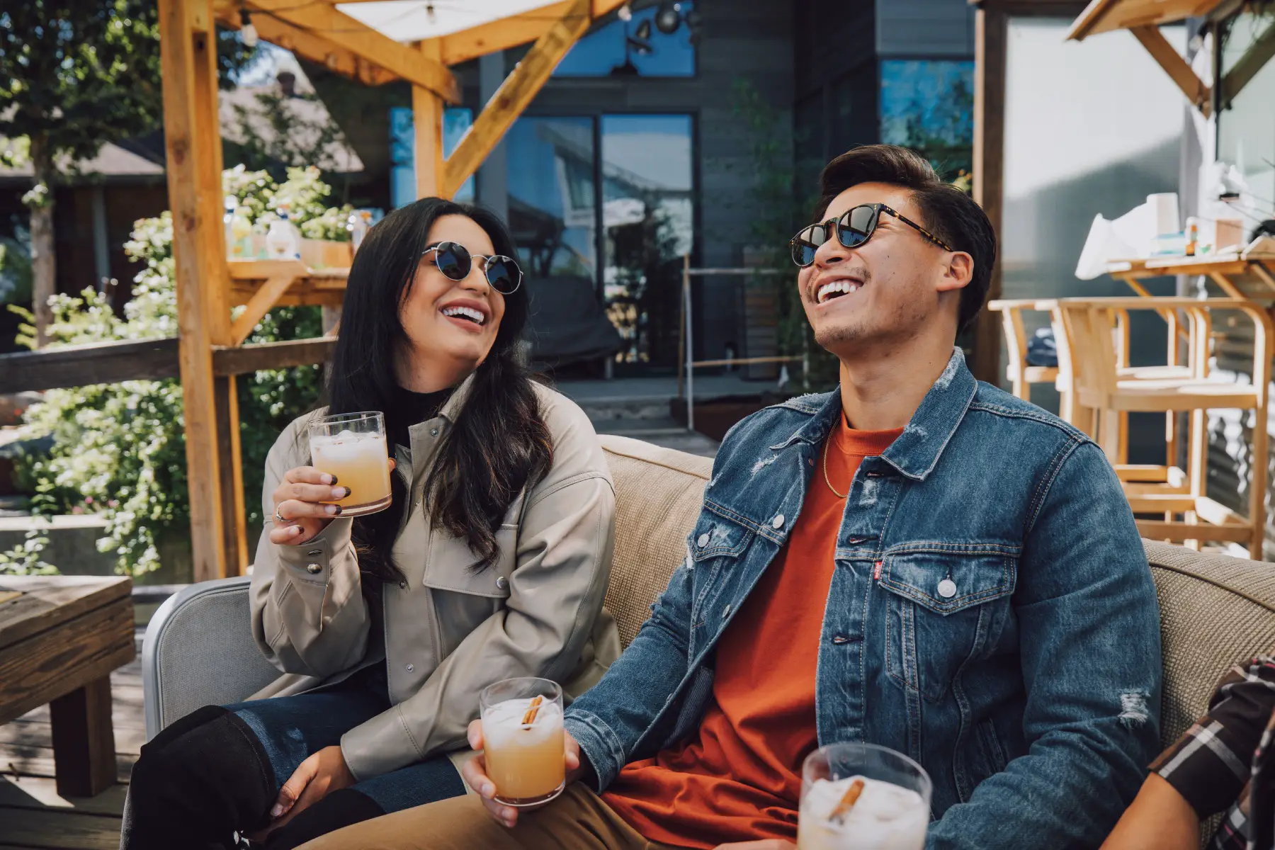 two single people (a man and woman) relaxing and laughing while enjoying a drink in a beer garden