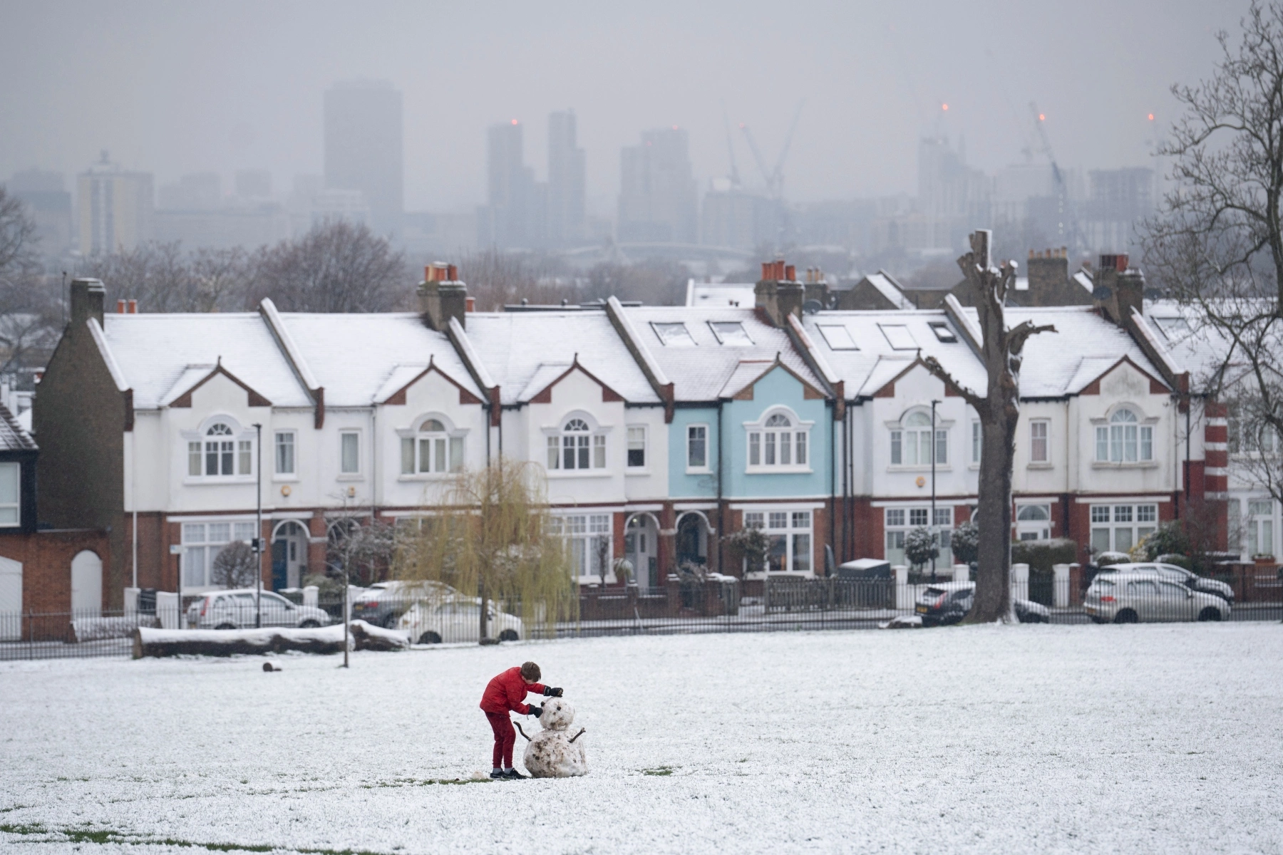 Man building snowman in Lambeth in snowy park