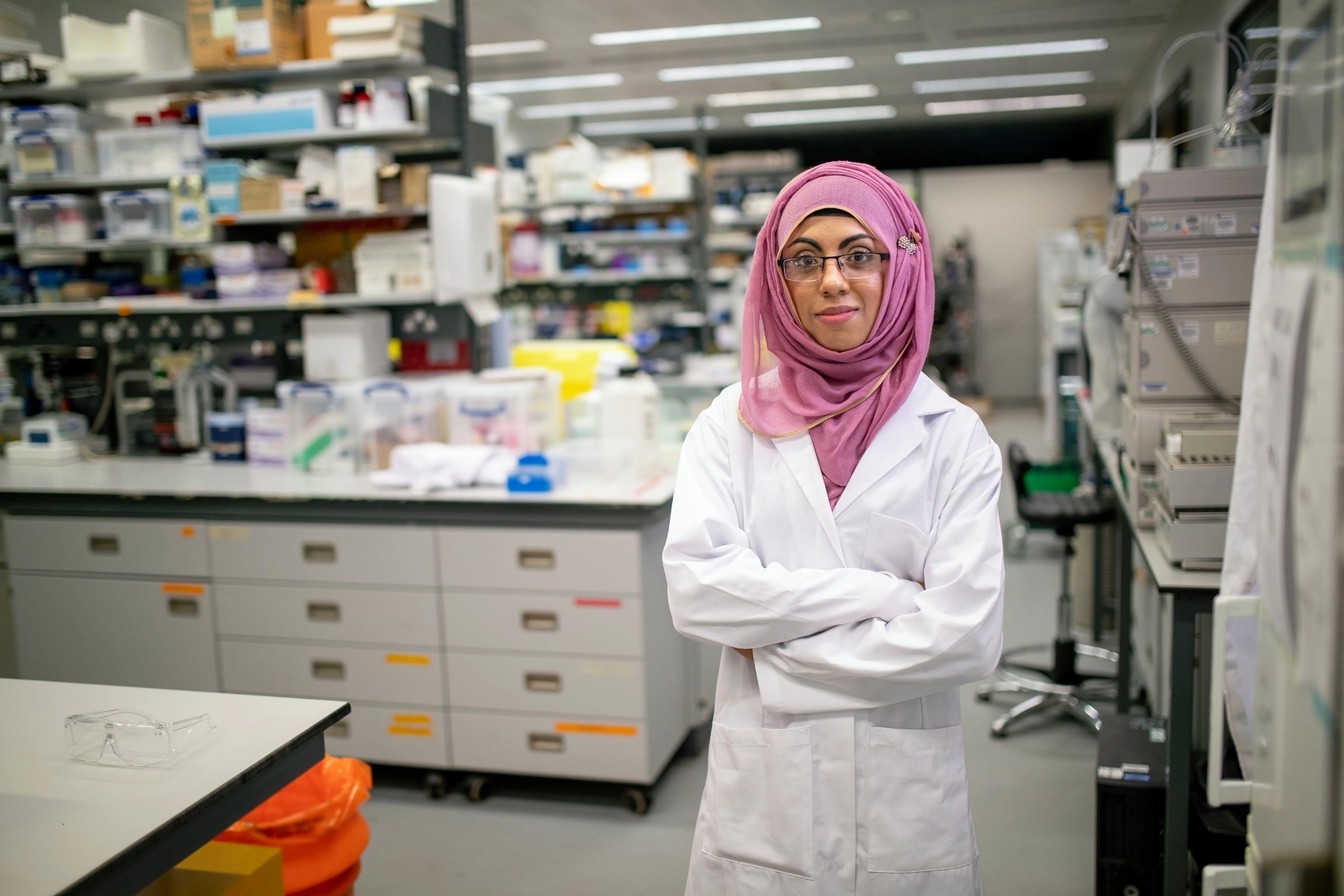 Biochemistry student standing in lab wearing lab coat and traditional hijab