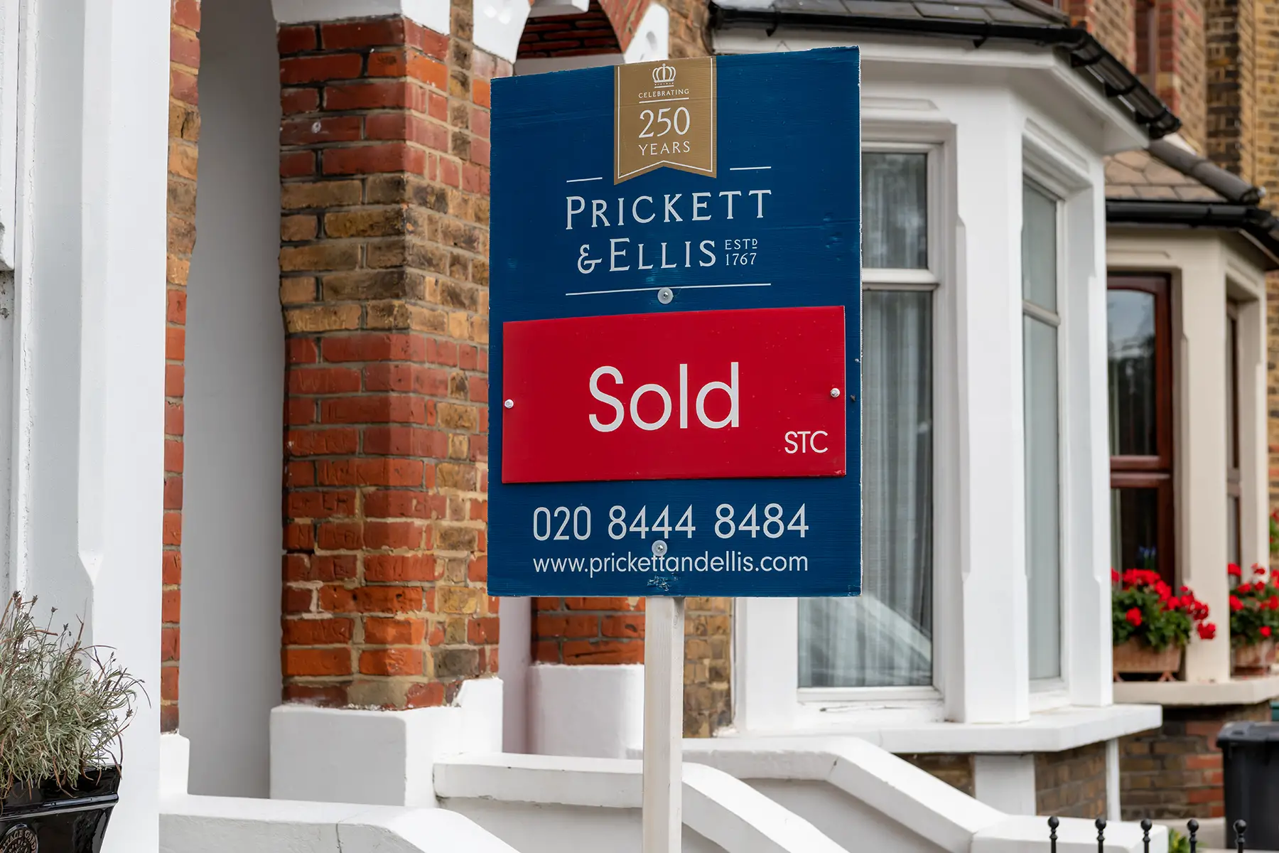 a property sold sign outside a suburban terrace house in London