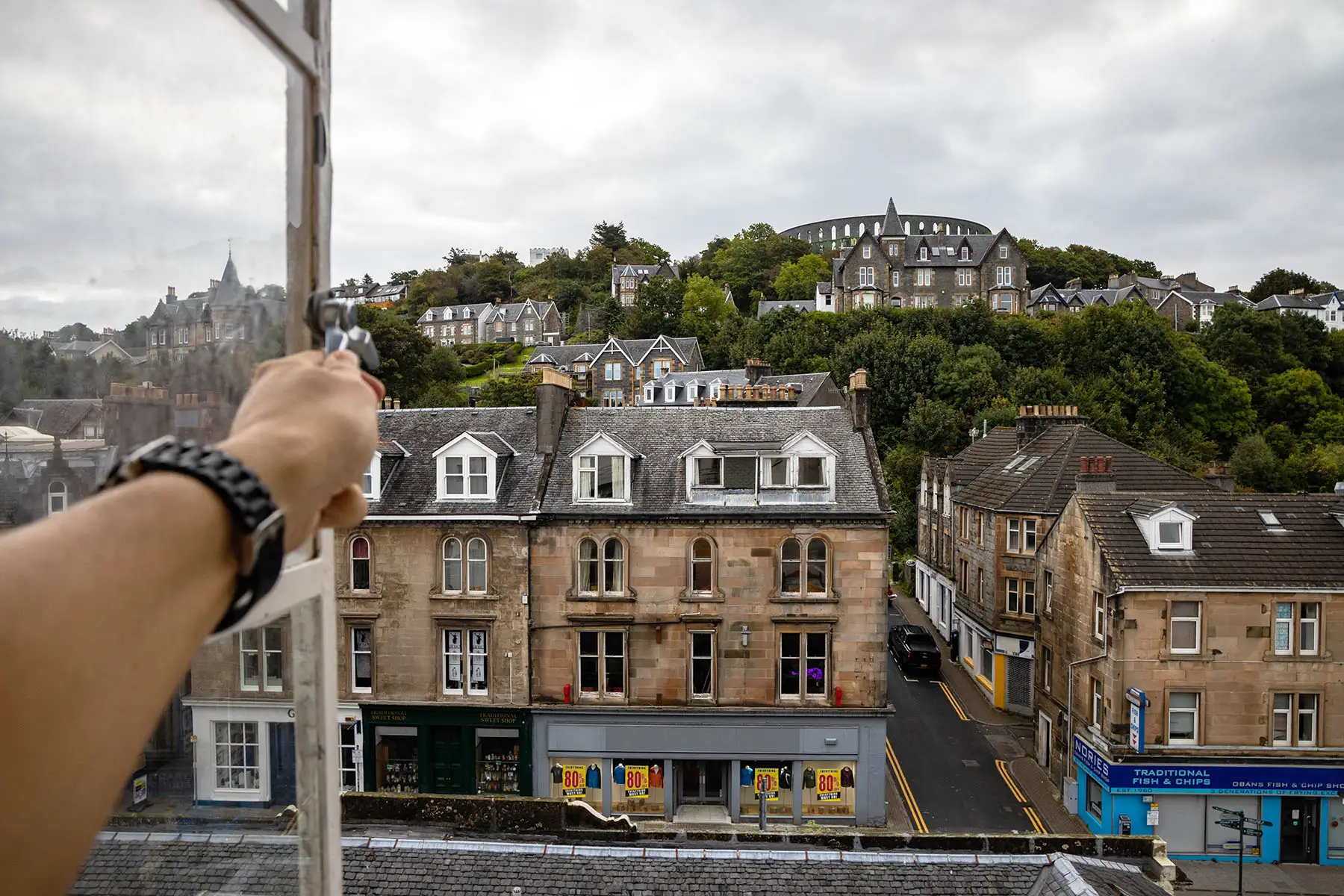 Person is opening a window to give a better view of the town of Oban, Scotland.