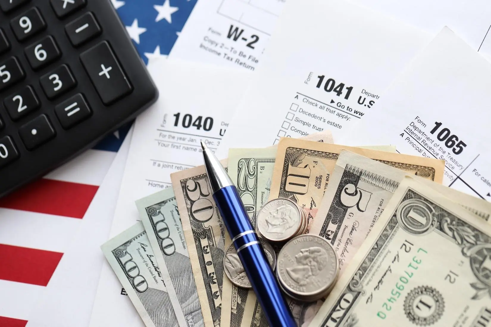 US dollar bills, coins, a calculator, and IRS tax documents