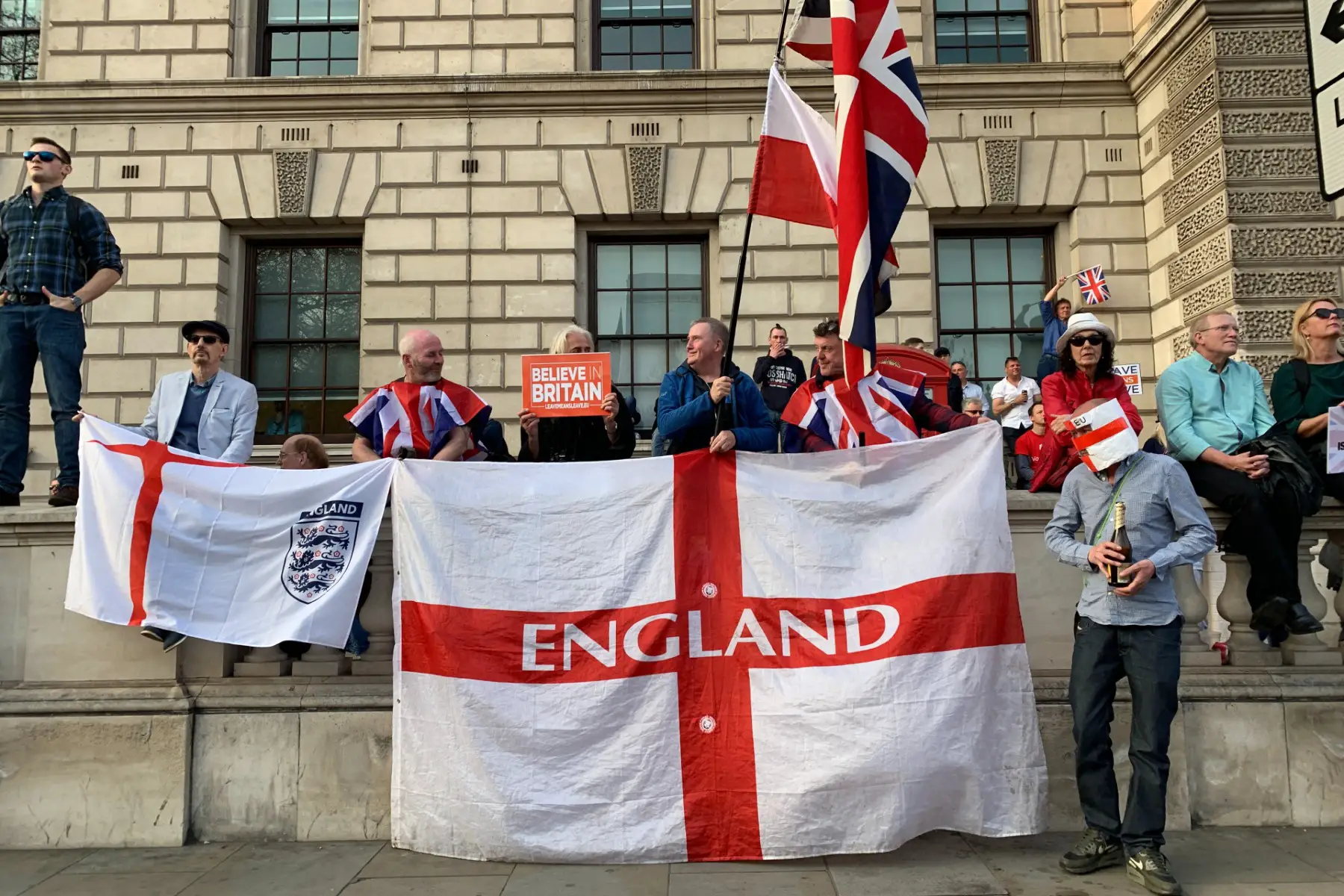 People holding an England flag and a sign that says 