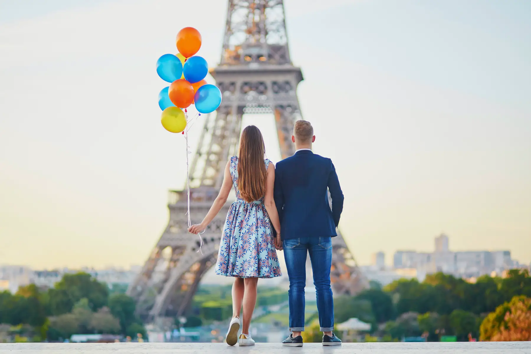 A couple holding hands in front of the Eiffel Tower