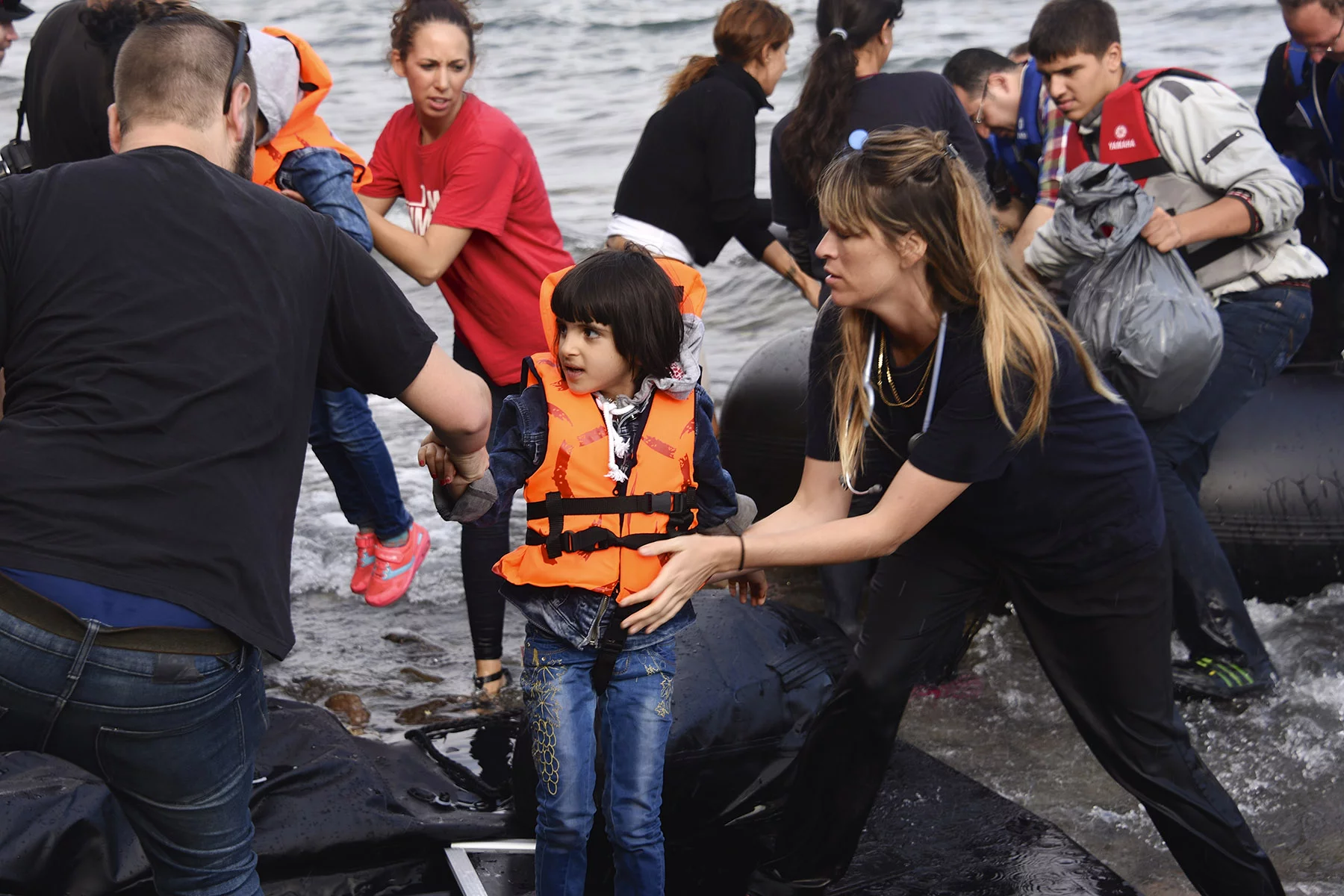 Volunteers helping a Syrian child refugee