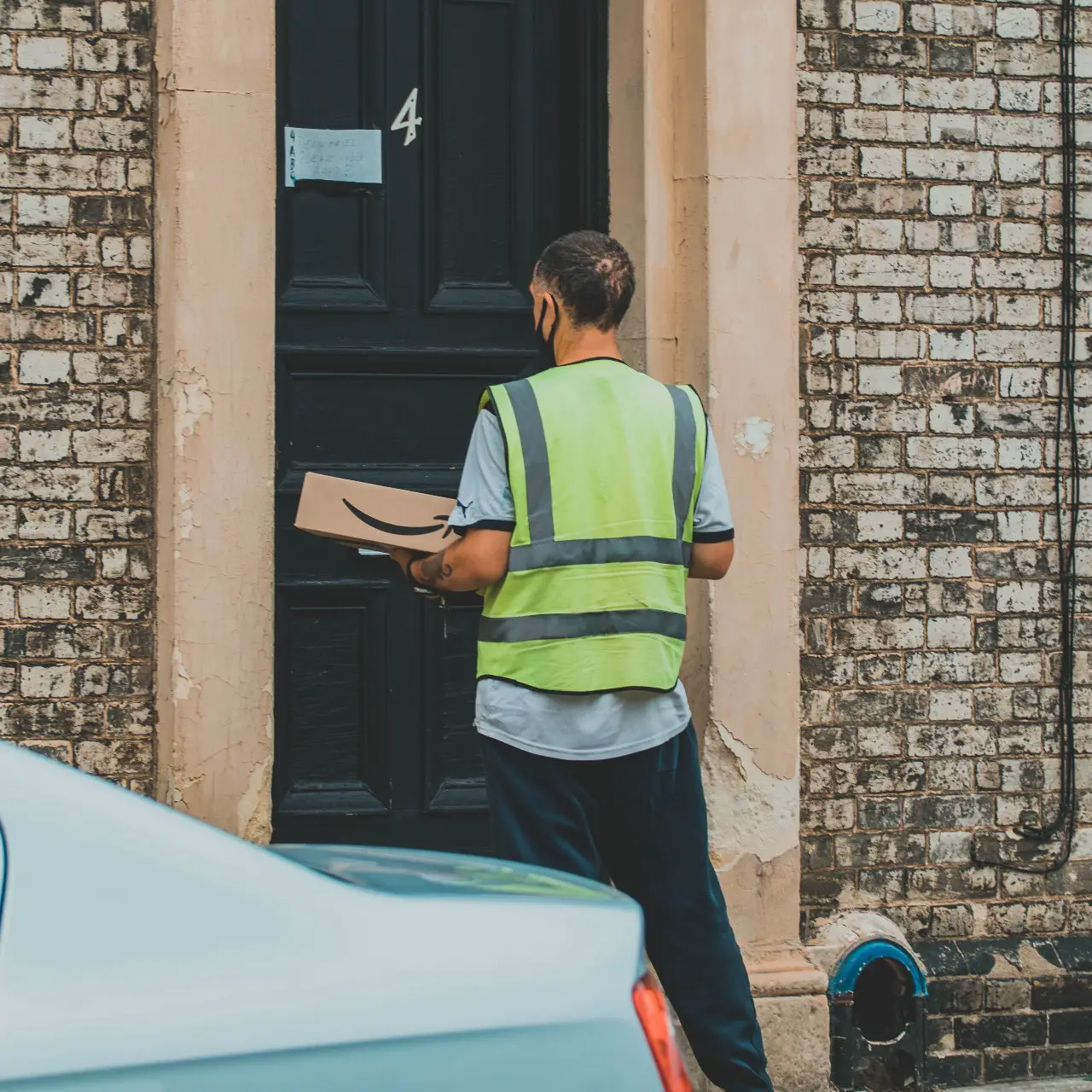 Man in green and yellow striped vest holding a package for delivery in Ipswich. 