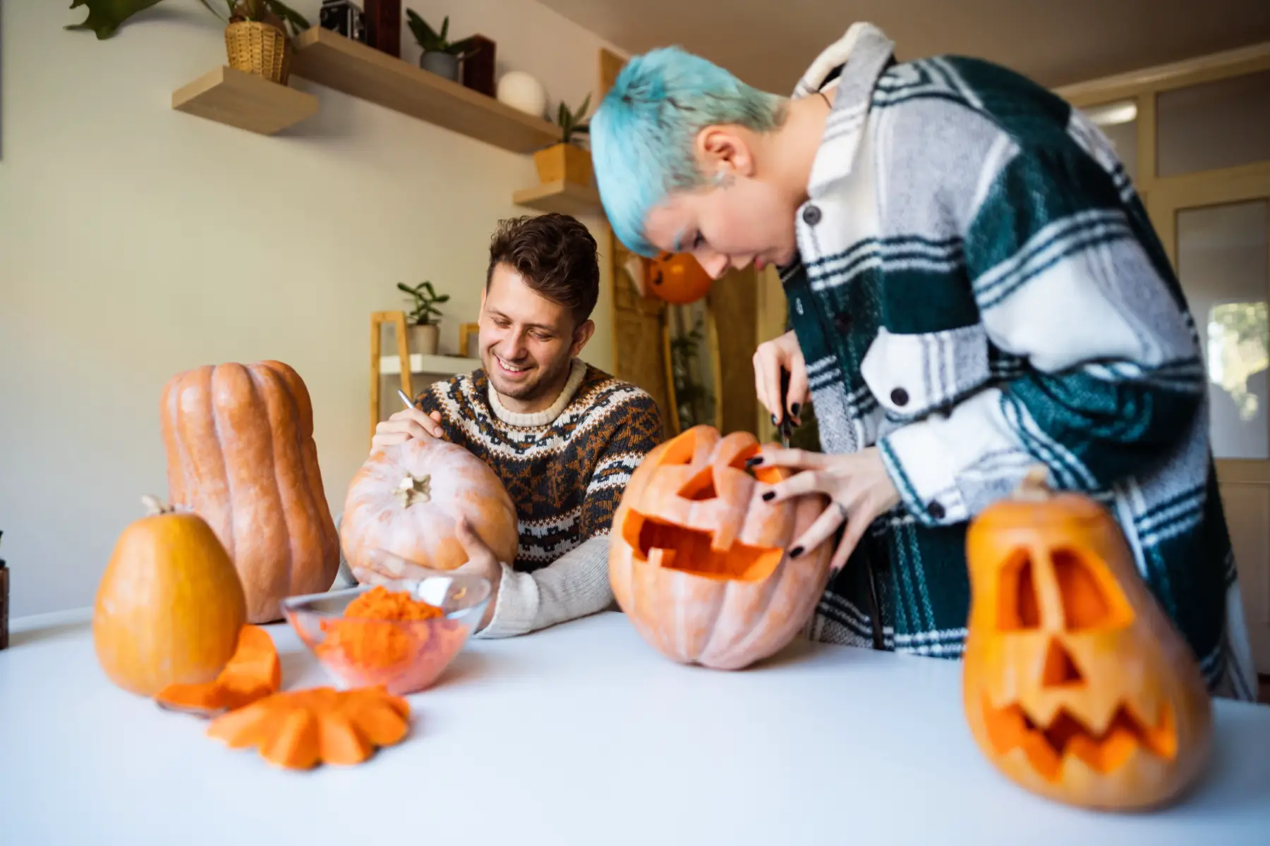 Young couple carving pumpkins together at home