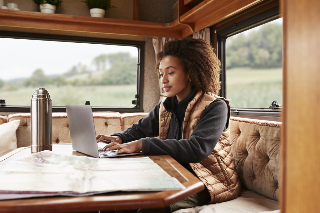 A young woman uses her laptop inside a camper van
