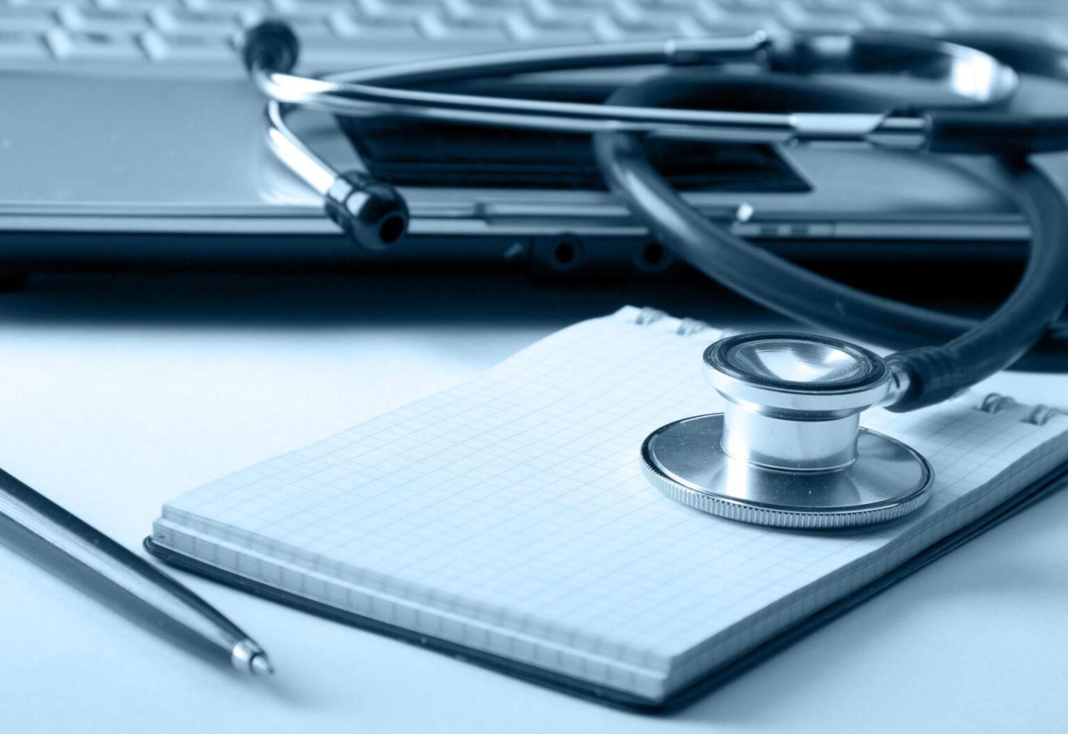 Stethoscope, notepad, and laptop on a desk, representing health insurance coverage for Brits living abroad.
