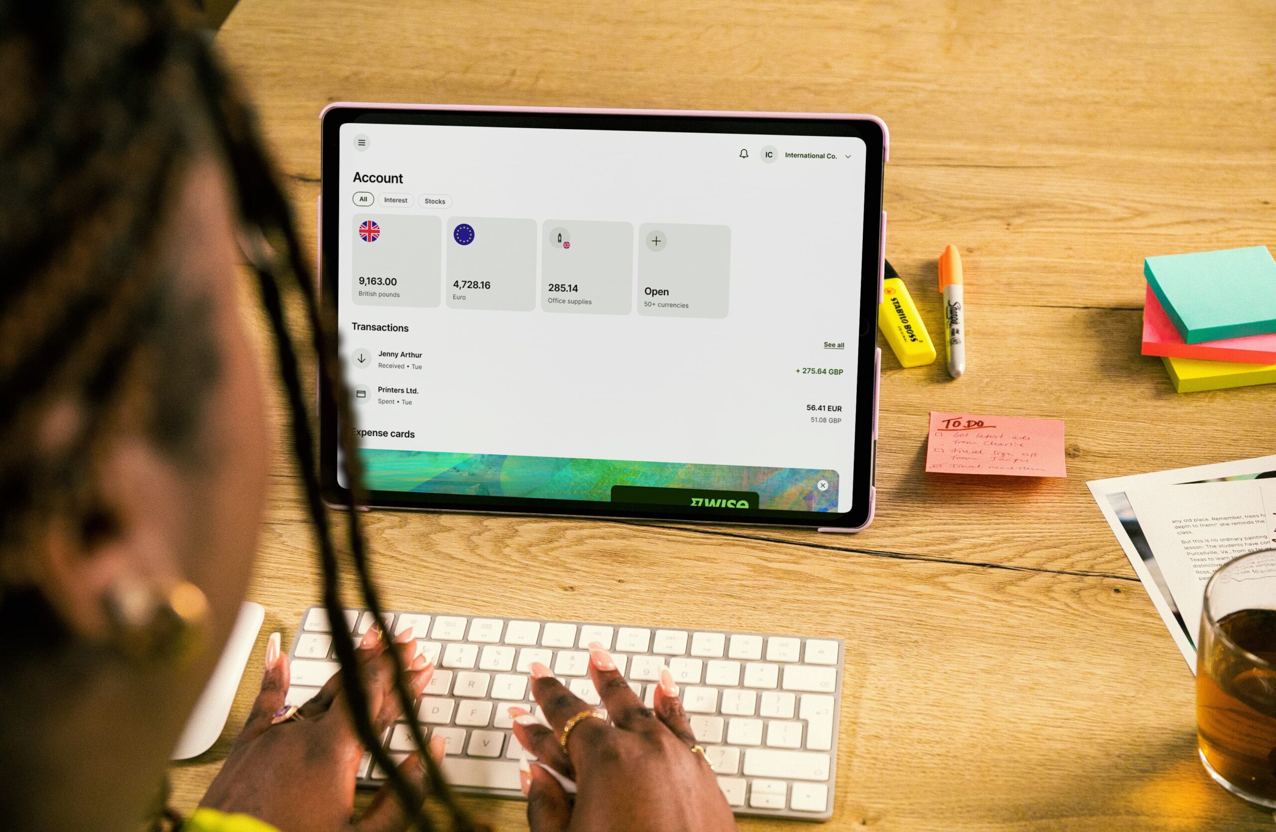 Woman sitting in front of a tablet managing her online currency account.