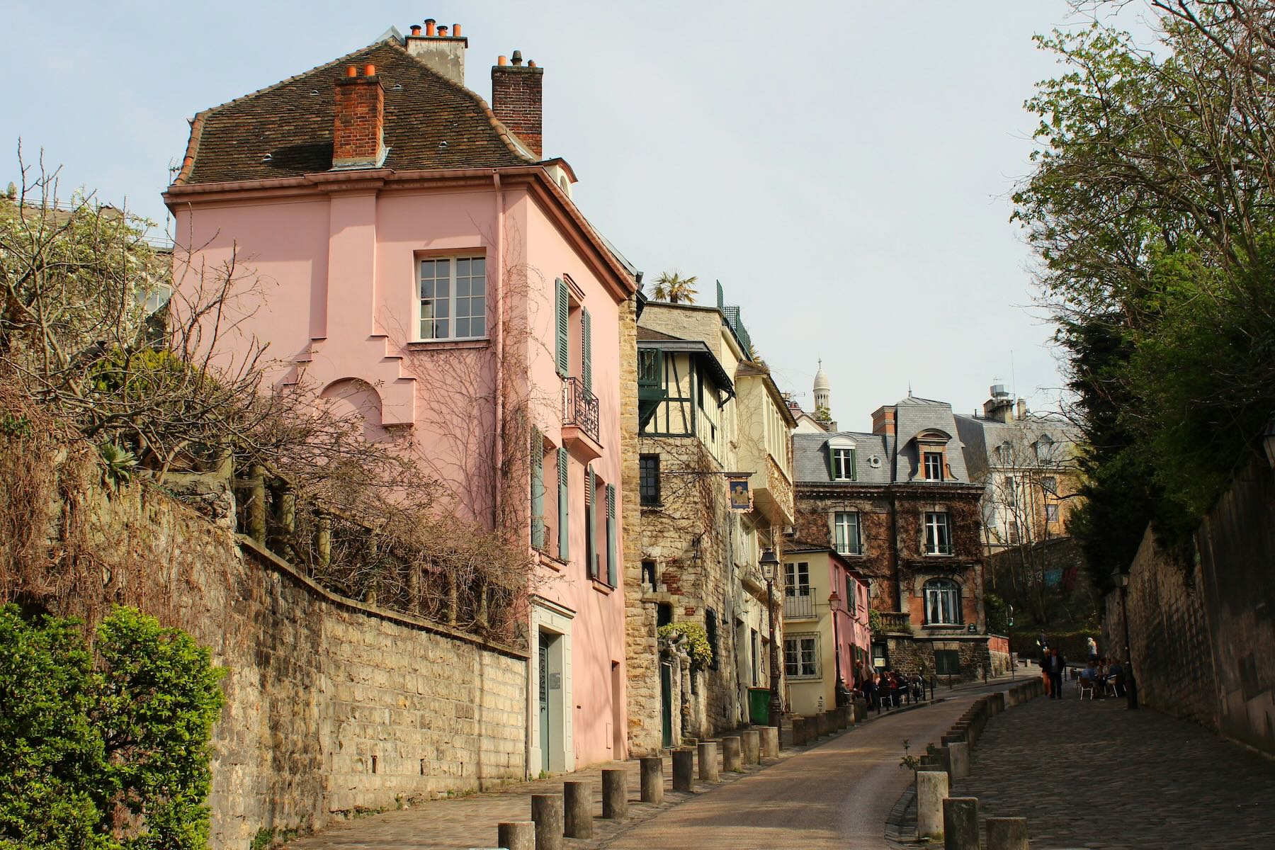 A small street in Montmarte, Paris, France with a light pink house on the end