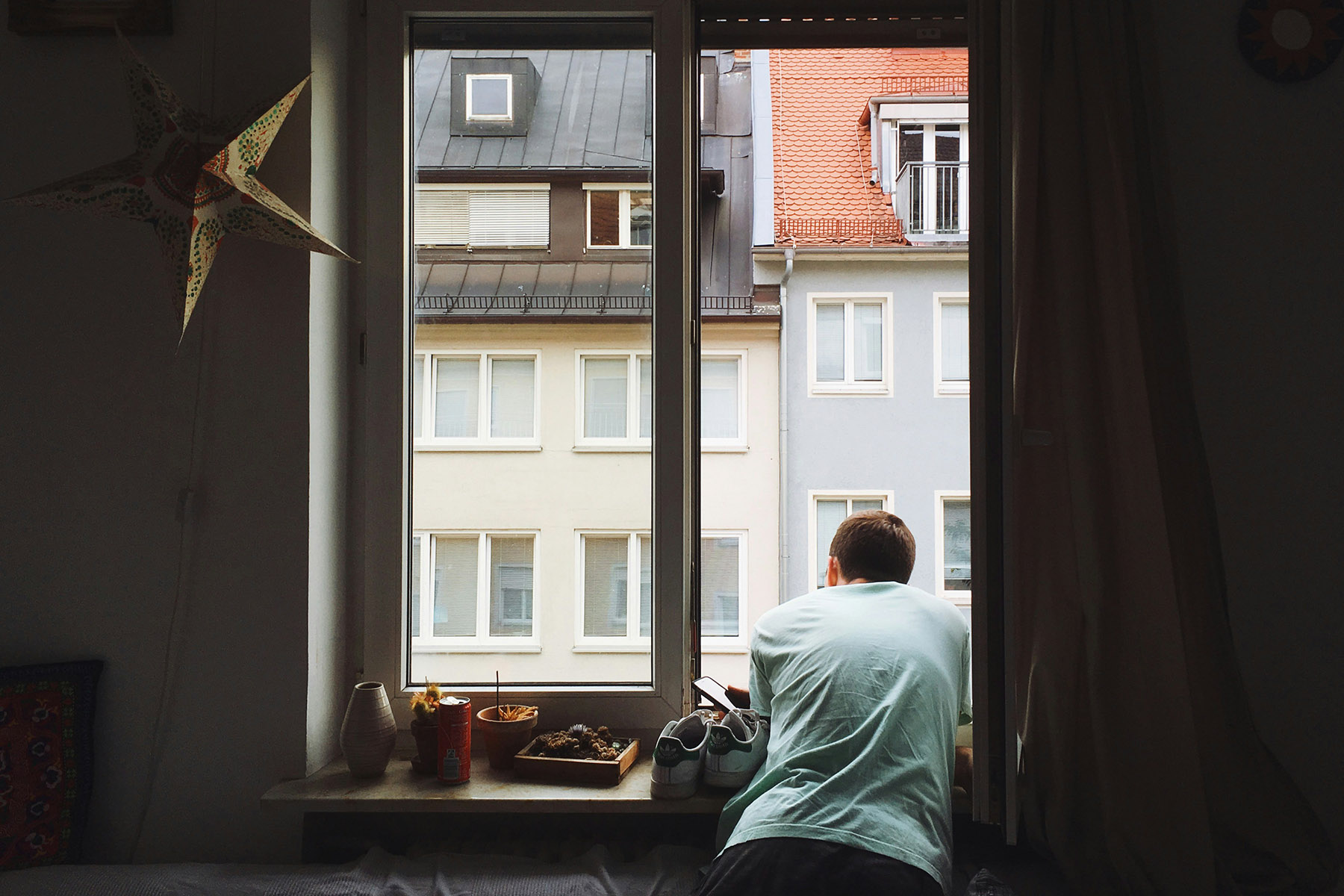Man hanging outside of a window, staring down.