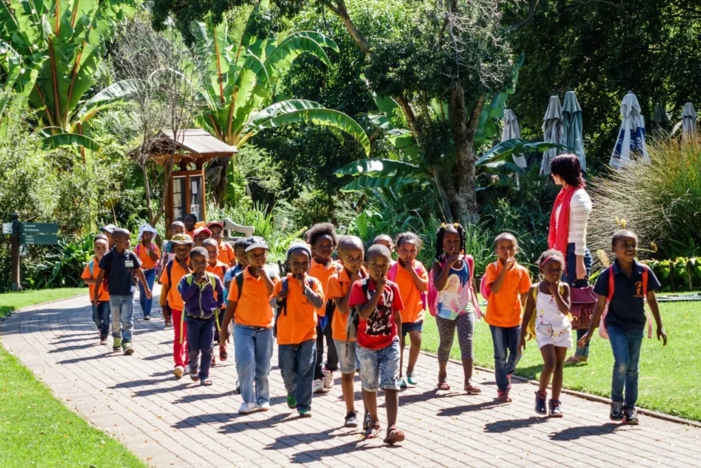 Large group of school children supervised by teacher walk through Walter Sisulu National Botanical Garden 
