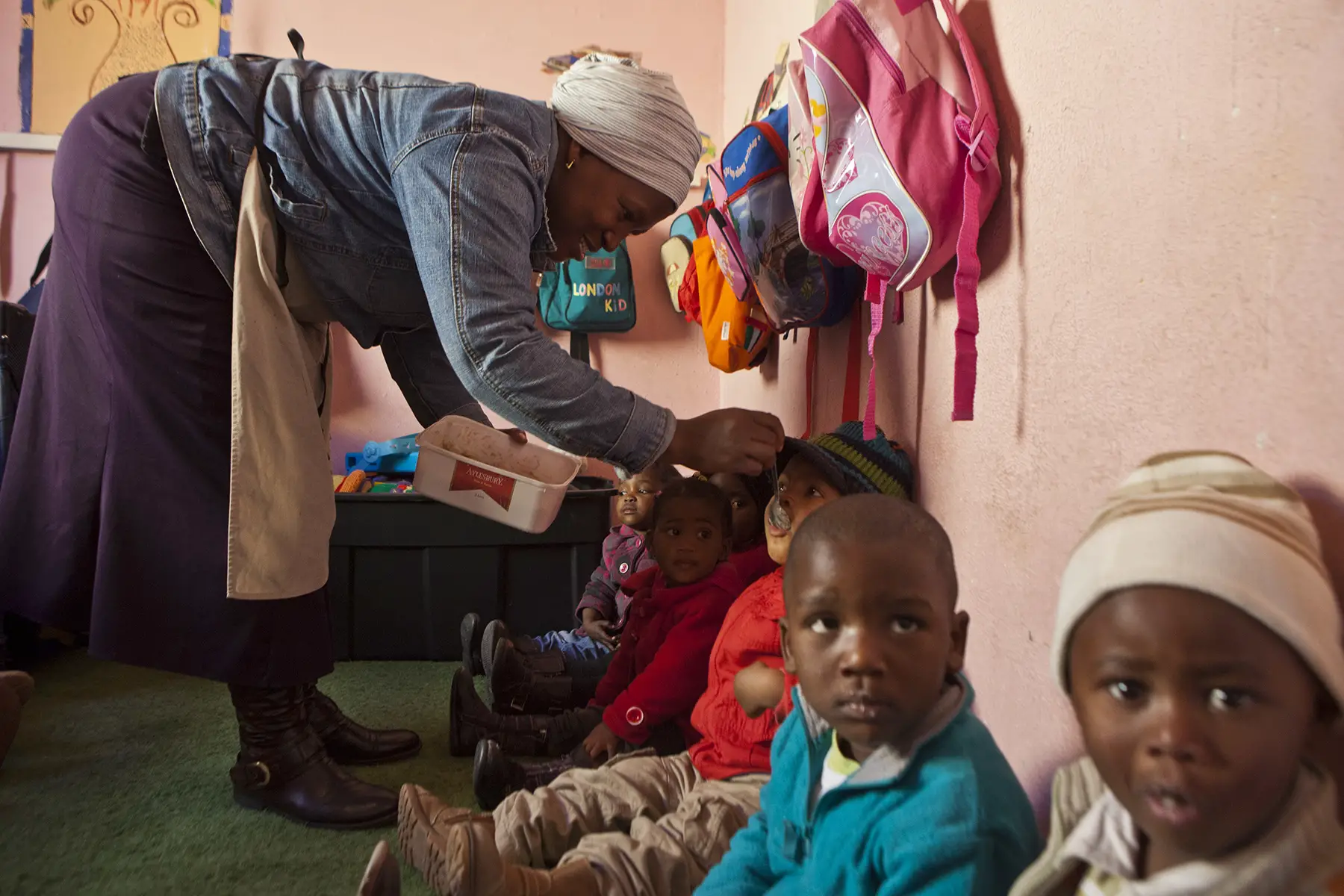Childcare worker feeds lunch to the kids at a daycare in Cape Town, South Africa