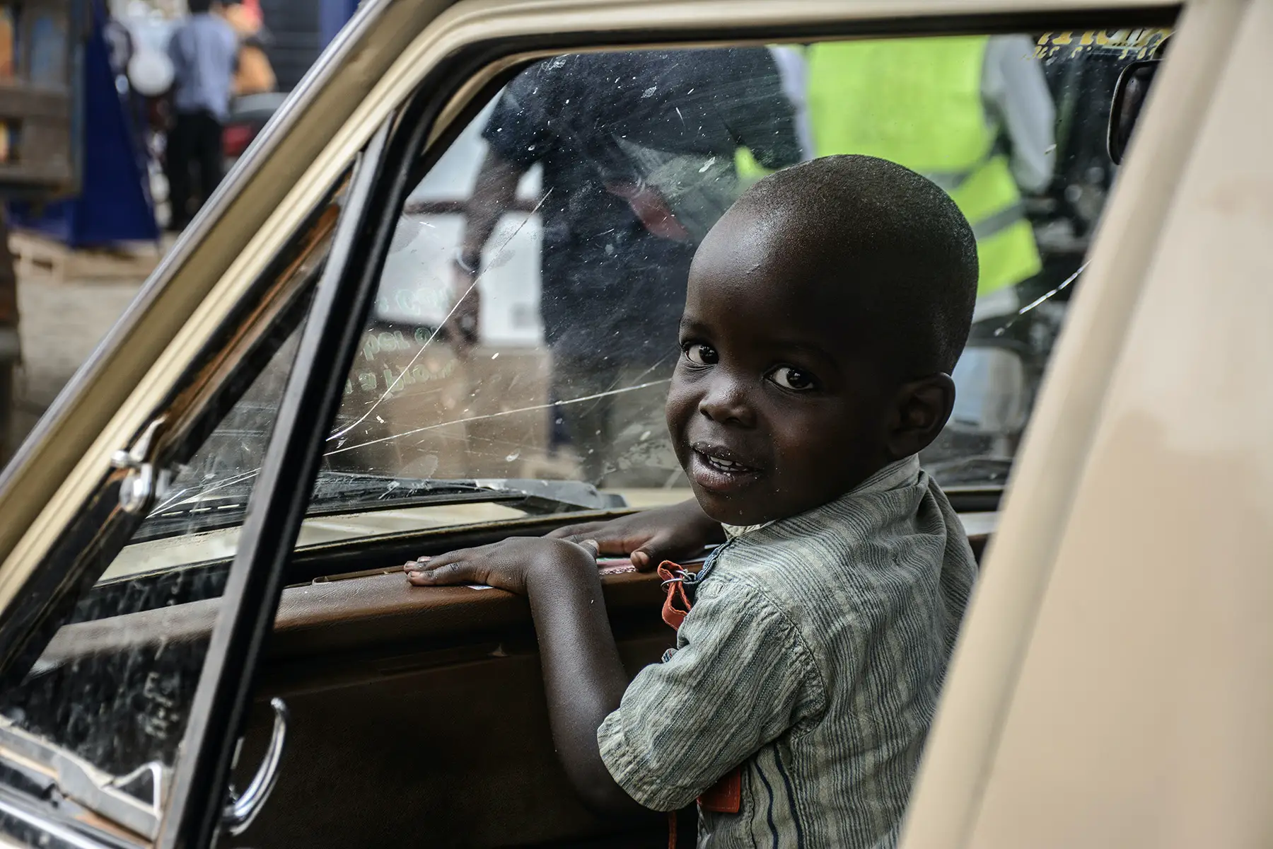 Little boy sitting in car, looks around and smiles at camera
