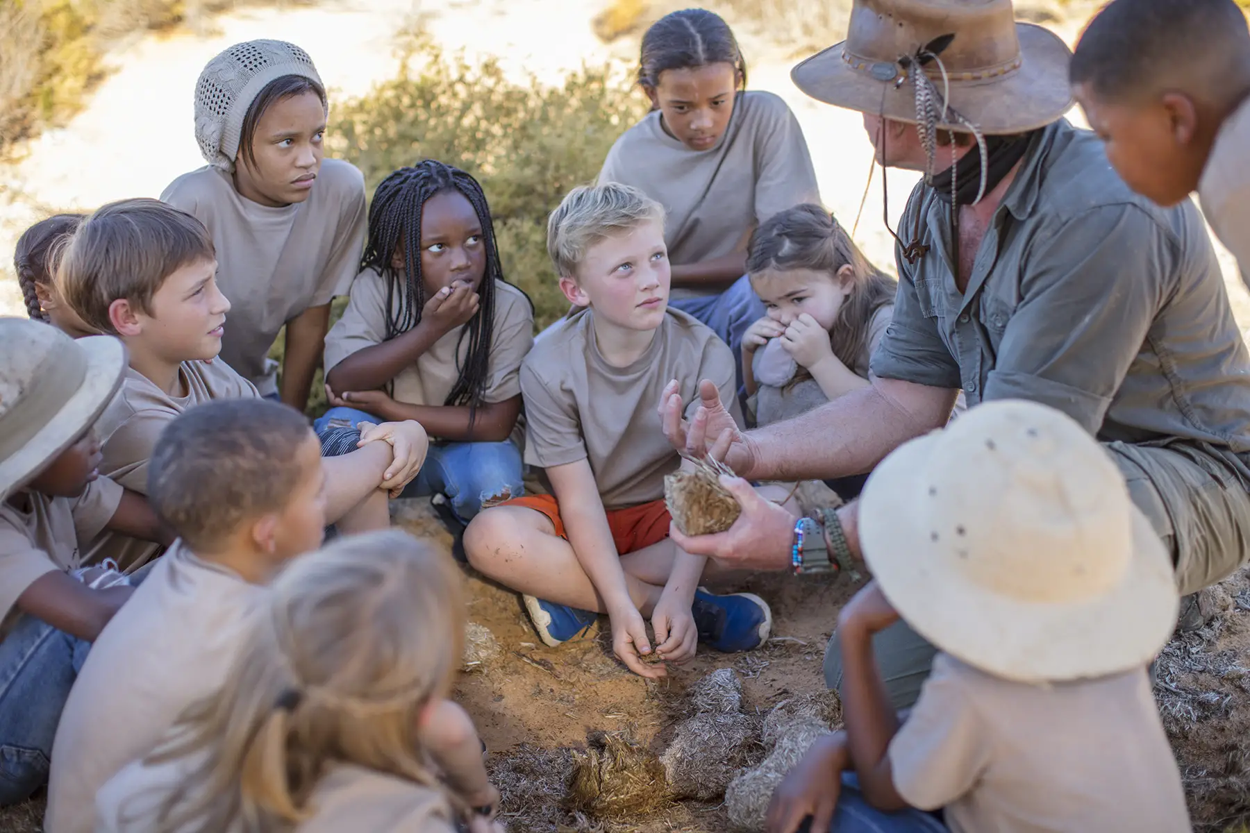 Children sitting outside in a nature reserve learning from a guide