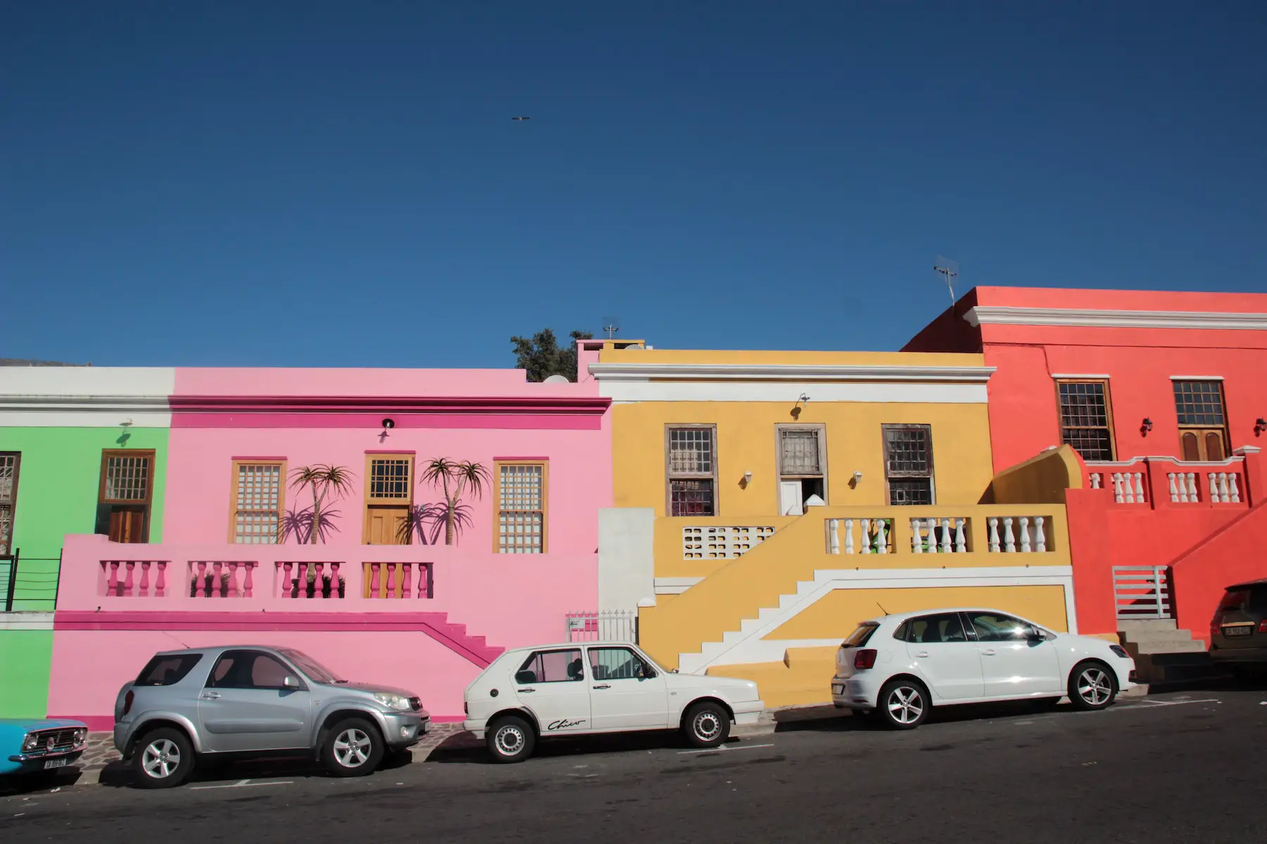 An inclined street is lined with colorful houses of similar shape and size, in Bo-Kaap, Cape Town