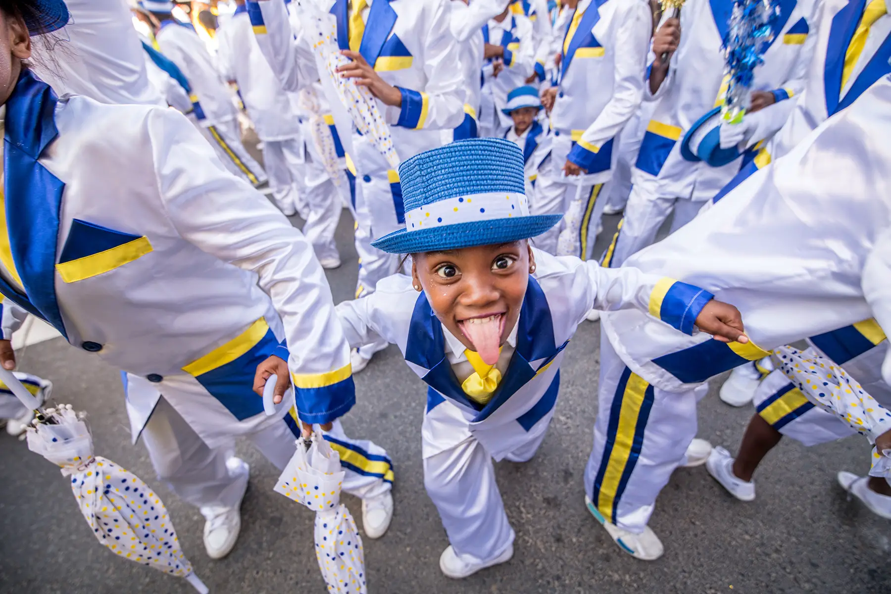 A young boy in white suite with blue and yellow details sticks his tongue out at camera. He is taking part in the Cape Minstrel Carnival (Kaapse Klopse) on the second day of New Year, a traditional parade in Cape Town