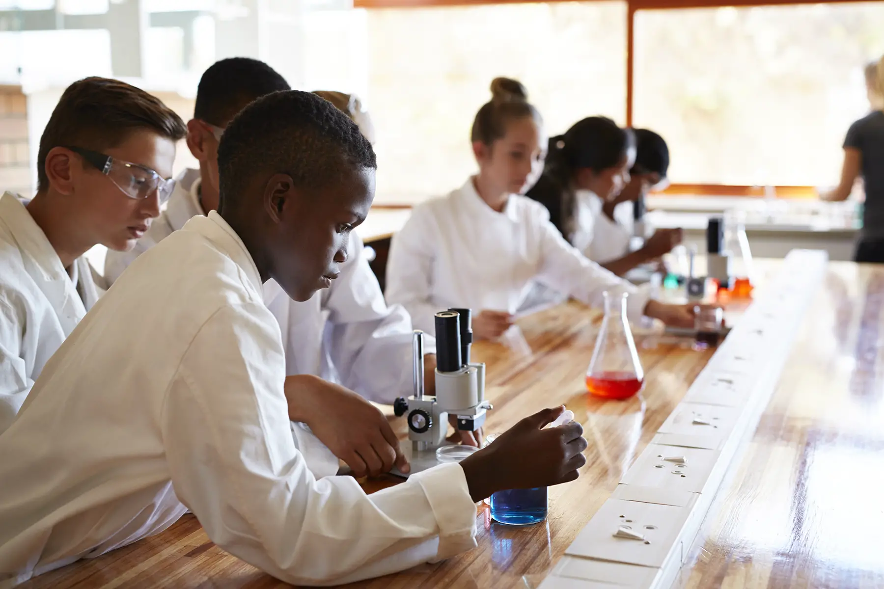 Students in lab coats working on experiments in the secondary school science lab