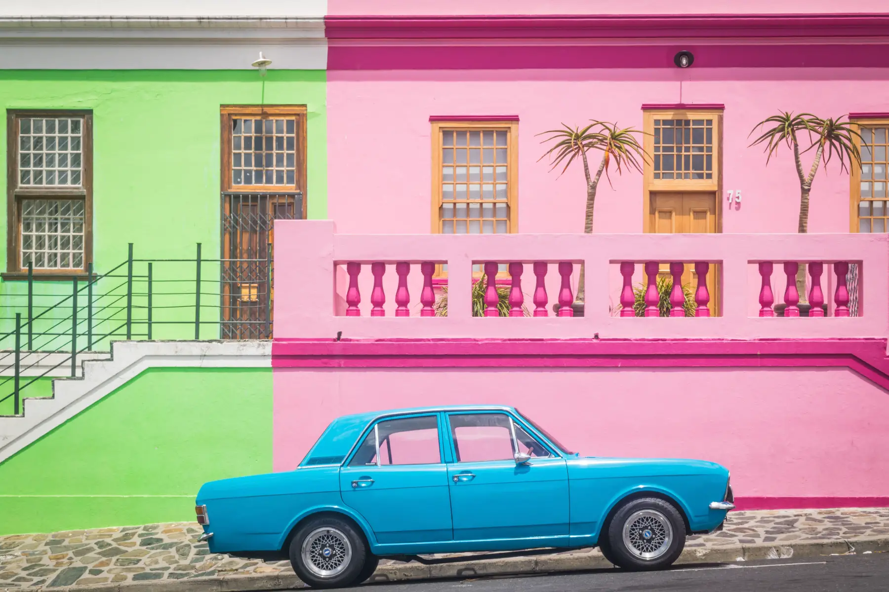 Bright blue vintage car in front of bright green and pink houses, Bo-Kaap, Cape Town