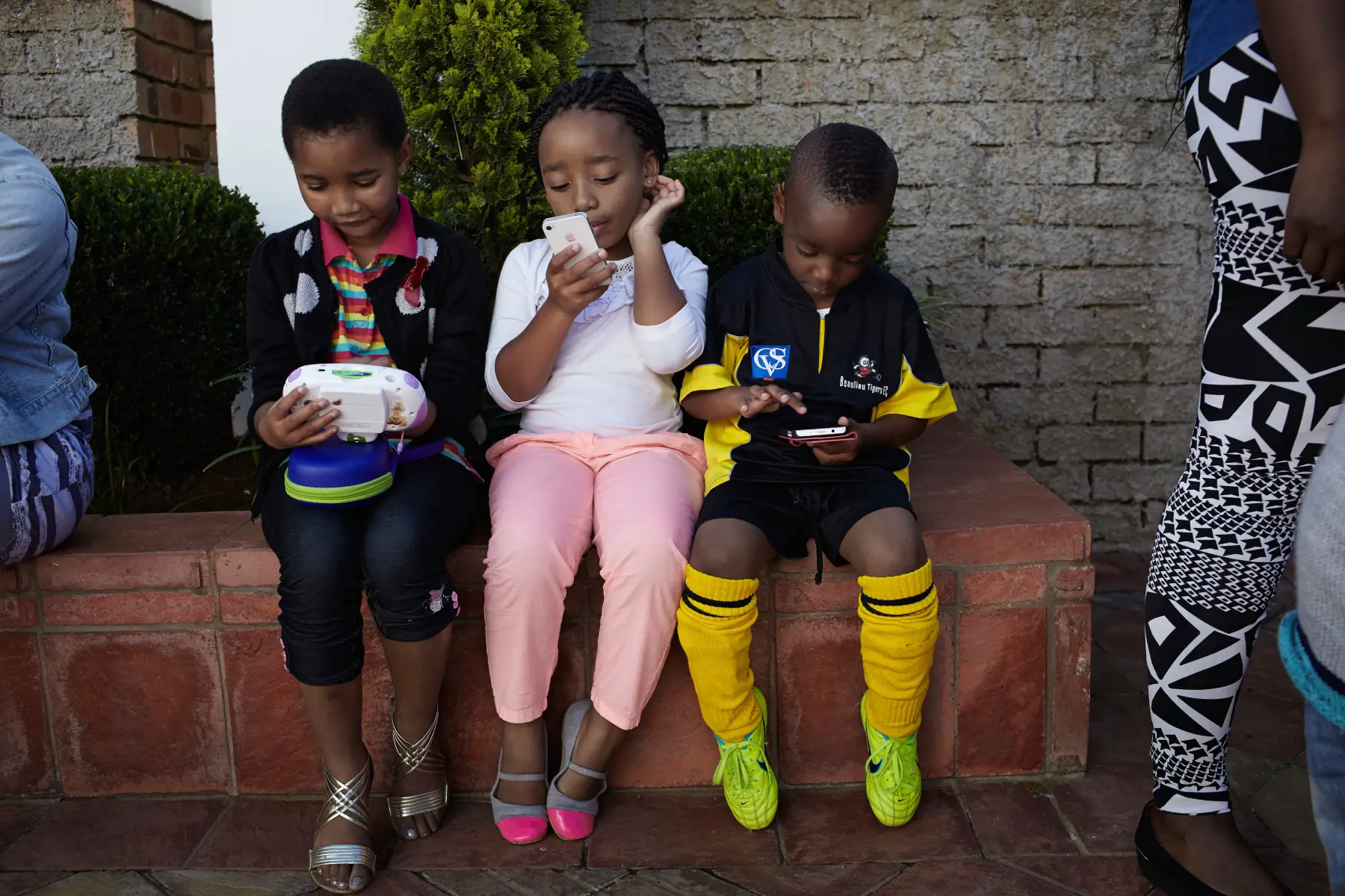 three little kids playing on mobile phones