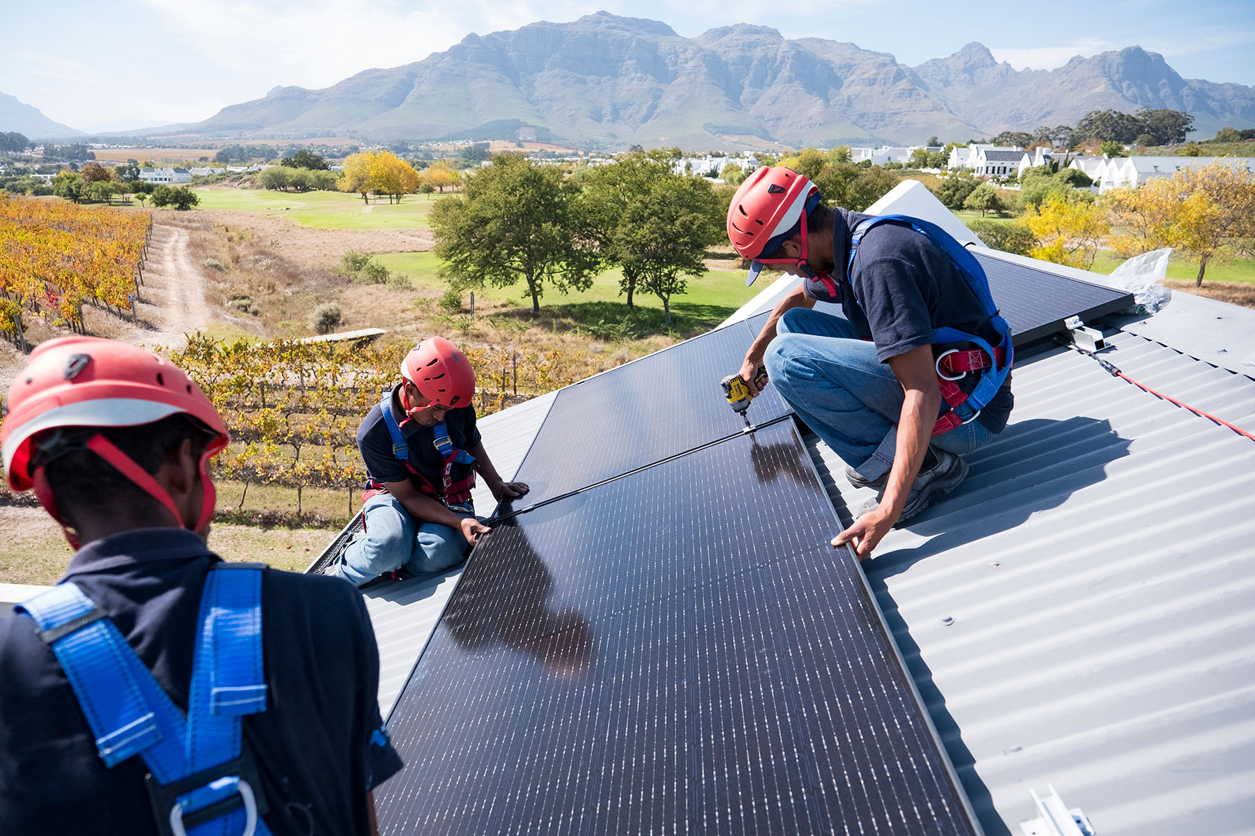 Technicians install solar panels on a roof of a home in South Africa