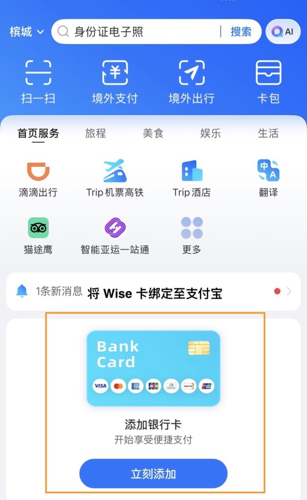 支付宝(Alipay)国际版应用的主页截图。页面顶部显示当前城市为“杭州”,并设有“扫一扫”、“付钱/收钱”、“出行”和“卡包”四个快捷功能。中间部分展示了 DiDi(滴滴)、Trip(携程)机票/火车票和酒店、翻译等实用工具。核心区域是一个“添加银行卡”的引导框,显示支持 Visa、Mastercard 等国际卡,下方还有“如何付款”和“如何使用支付宝出行”的教学指南。